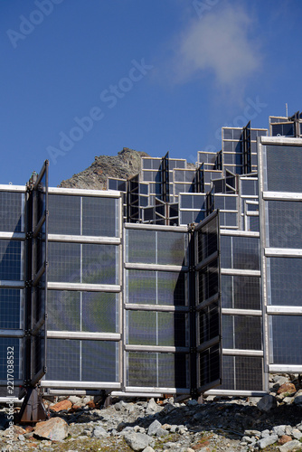 Detail of solar panels in mountains vertically mounted as four wings around central column like tree, photovoltaic plant avoid snow accumulation, future innovation energy concept