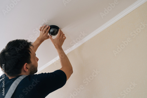 Professional worker hands installing modern dome security camera on ceiling, ensuring full monitoring and protection for residential or commercial property safety.