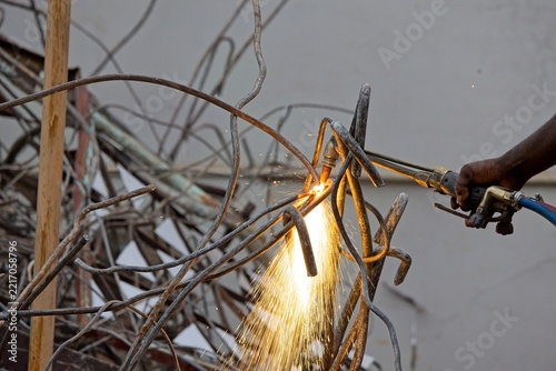 Sparks shower as worker cuts rebar with gas torch