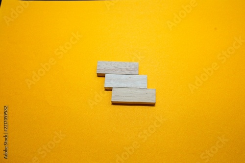 Wooden blocks arranged like steps on bright yellow surface