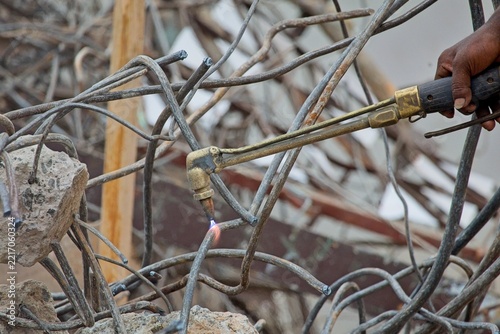 Worker using gas cutting torch on rebar at demolition site