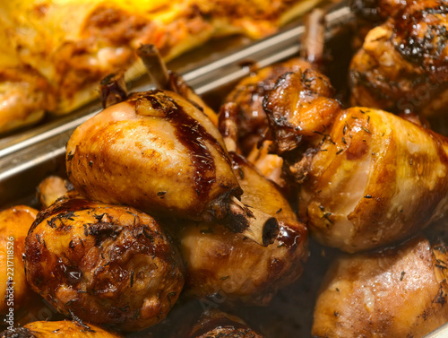 Chicken legs coated with teriyaki sauce and spices displayed in a grocery store deli, presenting cooked poultry arranged in a prepared food retail section
