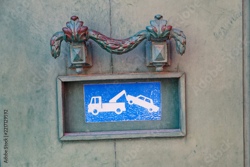 Vintage metal door with tow truck sign indicating no parking or towing zone