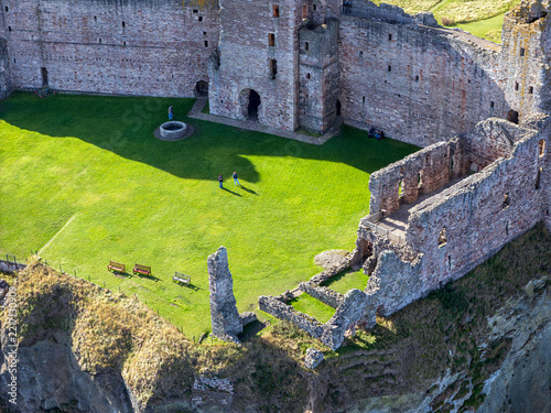 Aerial view of Tantallon Castle showing the grassy courtyard, stone ruins, and visitors walking on the grounds in North Berwick, Scotland, United Kingdom.