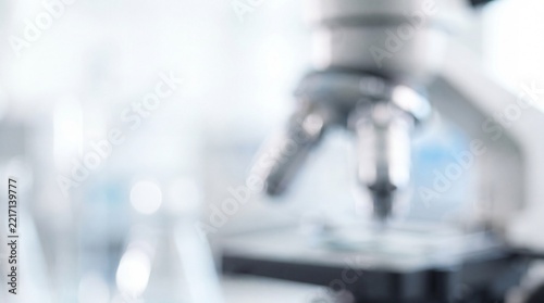 Blurry laboratory microscope in a bright scientific medical research facility with soft bokeh lighting and clean white background.