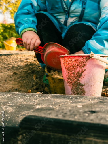 Close-up of toddler filling bucket with toy shovel
