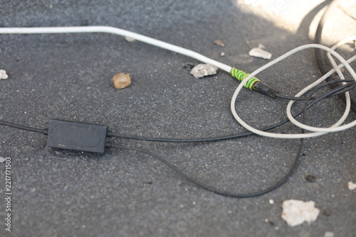 Tangled electrical cables and wires lying on a rough gray concrete surface outdoors