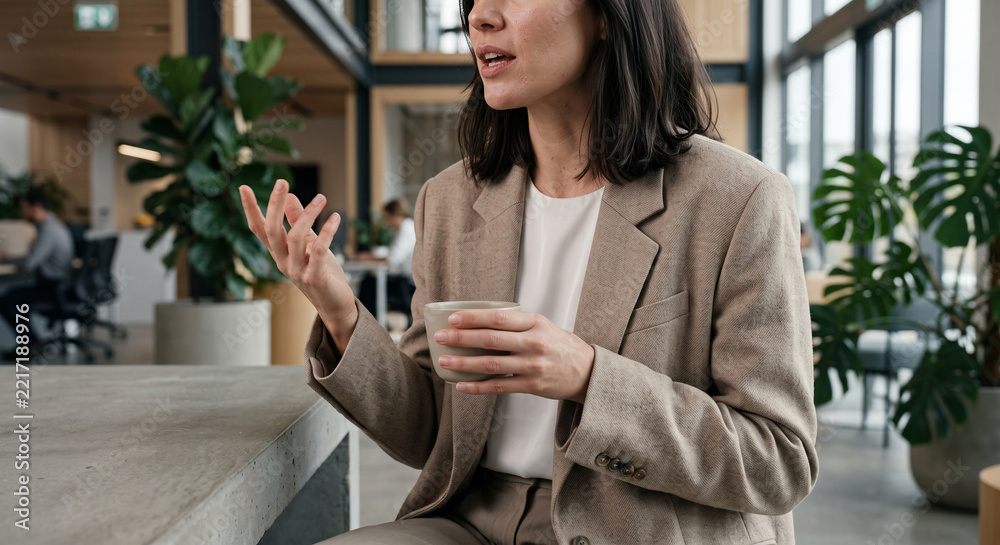 Fototapeta premium Unrecognizable Businesswoman Gesturing While Holding A Coffee Cup During A Meeting In Modern Corporate Office