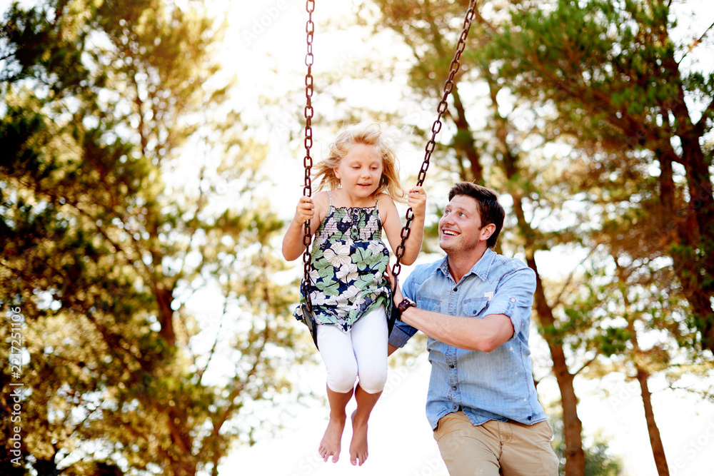 Fototapeta premium Father, child and happy on swing at park for playing together, freedom and holiday adventure. Family fun, dad and push girl kid on playground equipment for bonding, sensory stimulation and adrenaline