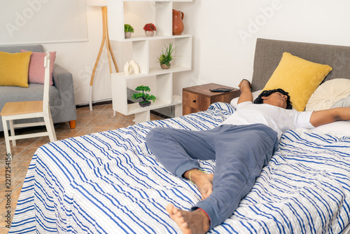 Young man waking up stretching in bed