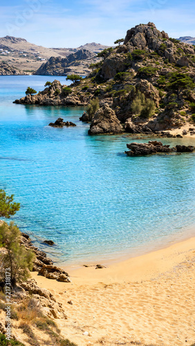 Idyllic Beach Scene at Mikri Vigla: Captivating Sandy Shoreline Merging with Turquoise Waters and Surrounding Rocky Outcrops on a Bright Sunny Day in the Cyclades