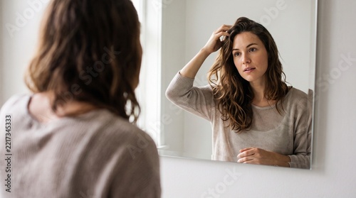 woman looking at herself in the mirror with her hand in her hair