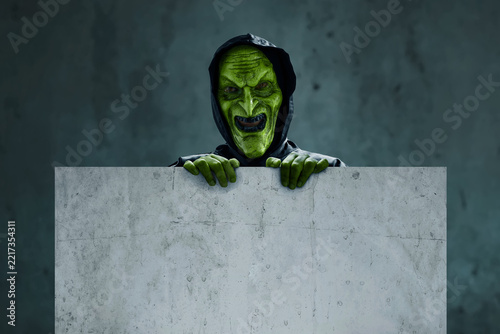 Scary witch holding empty blank sign board, Halloween theme