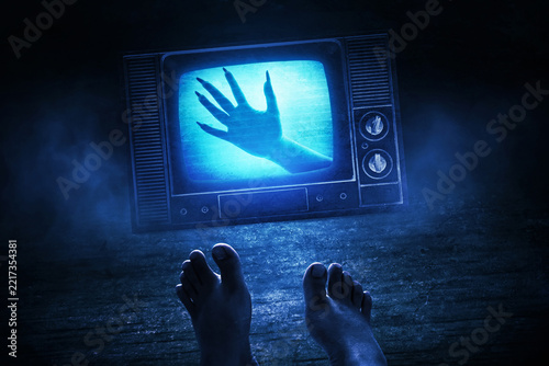 Scary ghost hand coming out of old retro television screen