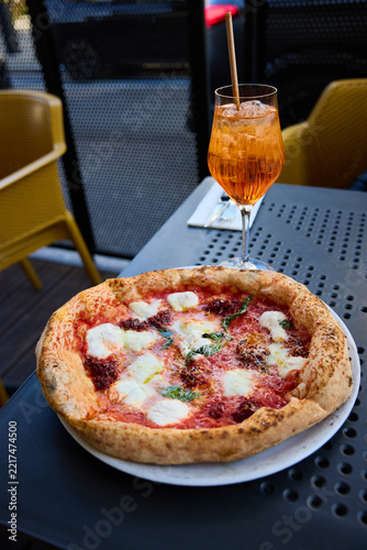 Delicious Neapolitan Pizza and Refreshing Aperol Spritz Cocktail on a Sunny Terrace