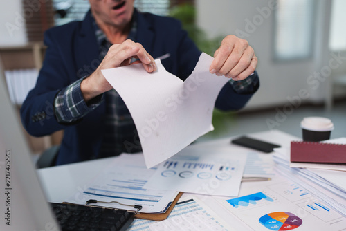 Frustrated businessman tearing paper feeling work stress