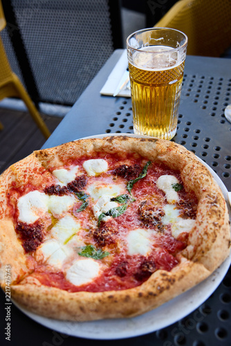 Delicious Neapolitan Pizza and Cold Beer on a Sunny Outdoor Terrace Table