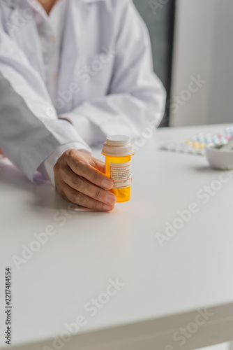Mature Asian pharmacist show medicine bottle on table
