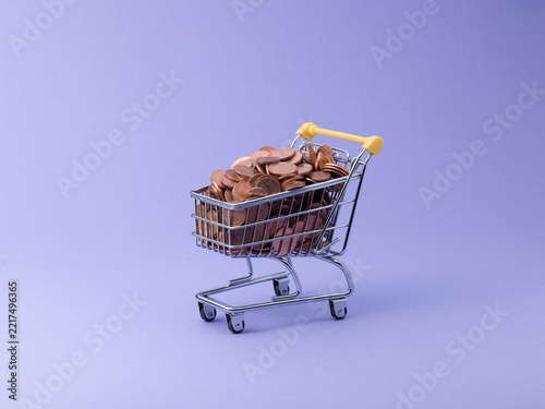 Miniature Shopping Cart Filled with Euro Coins on Purple Background