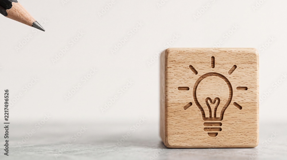Fototapeta premium Close Up of Wooden Block with Light Bulb Icon Representing Creative Idea and Innovation, Pointed by Pencil Tip on Neutral Background for Business Brainstorming and Solution Concept