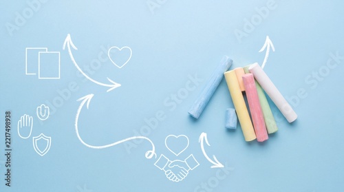 Top View of Colorful Chalk Sticks on Blue Background with White Line Art Icons Representing Strategy, Teamwork, Care, and Education Concept for Creative Business and School Presentation