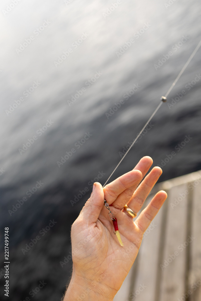 Fototapeta premium Close up of a hand holding a fishing lure over the water