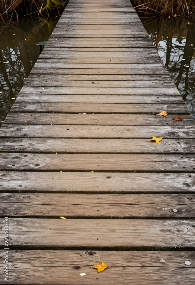 Fototapeta premium Mindfulness and tranquility wooden pier over calm water with autumn leaves for meditation nature escape travel journey and peaceful solitude