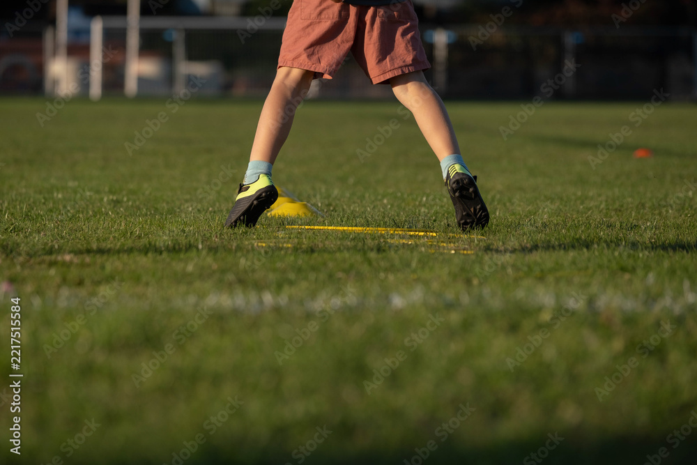 Obraz premium Child wearing football cleats during agility training drill