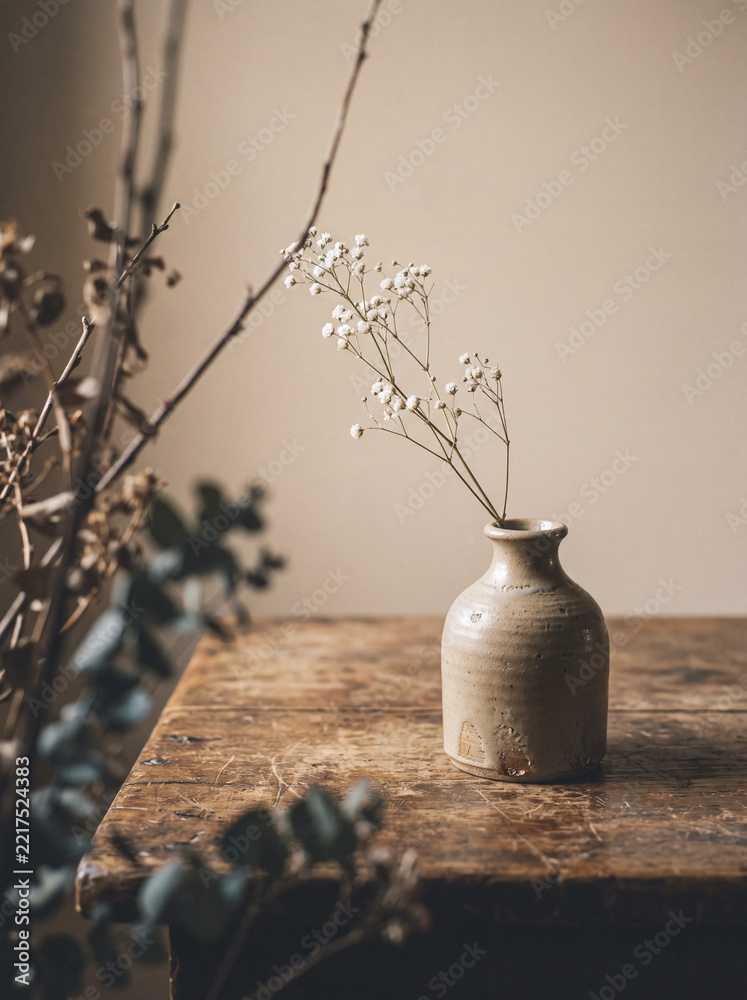 Fototapeta premium Rustic ceramic vase with baby's breath flowers on aged wooden table