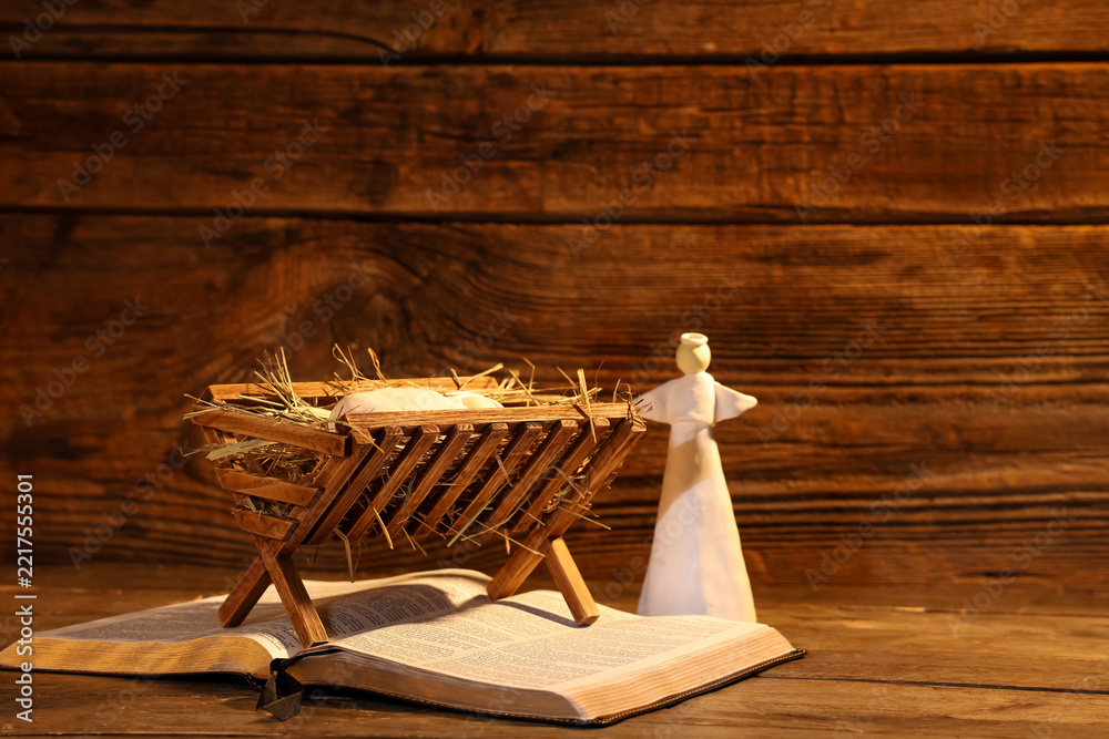 Fototapeta premium Manger with baby Jesus, Holy Bible and angel on wooden table