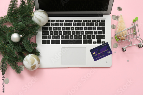 Composition with modern laptop, credit card and Christmas decorations on pink...