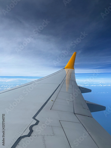 Wing tip of the plane against the blue sky and white clouds in sunny weather. 