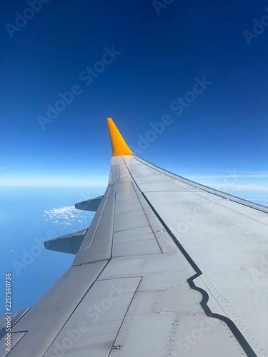 Wing tip of the plane against the blue sky and white clouds in sunny weather. 