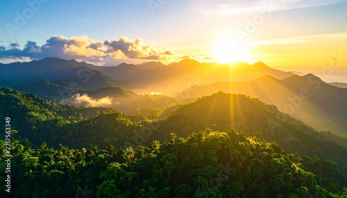 Sunrise over a lush green mountain range, with the sun's rays casting a golden glow over the landscape