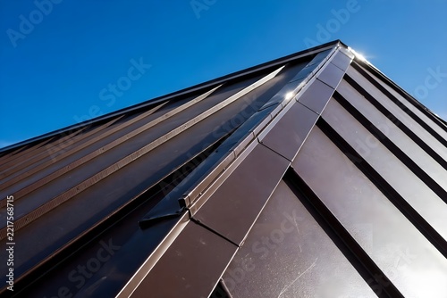 Dark metal standing seam roof ridge against blue sky