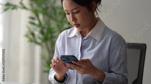 Asian businesswoman using smartphone application at office desk