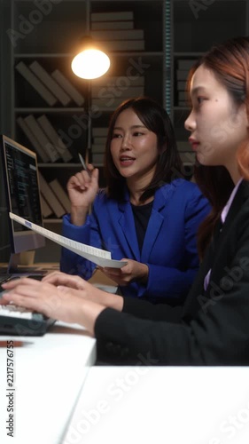 Two female programmers collaborating on coding project at night