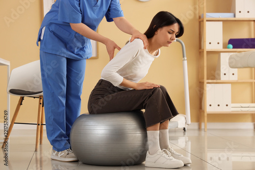 Back pain relief and physical therapy, physiotherapist examining patient sitt...