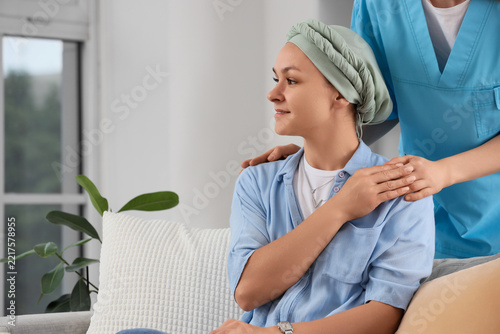 Cancer recovery and patient support, nurse comforting young woman with headsc...