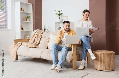 Online shopping and remote work, couple using laptops and credit card for hom...