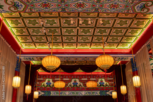 Ornate Traditional Chinese Ceiling with Patterned藻井 (Zaoding) and Hanging Paper Lanterns in a Cultural Performance Hall