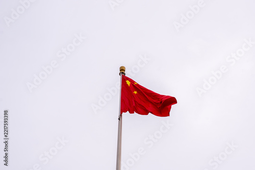 Chinese national flag waving in wind against overcast sky on flagpole