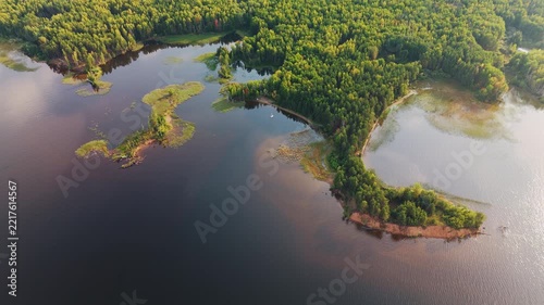 Aerial view of the coast of the lake covered with dense forest of mixed autumn trees. Sailing boat is visible in the frame. Votkinsk reservoir of the Kama river in Russia