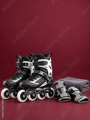 Black and White Inline Skates with Wrist Guards and Towel on Maroon