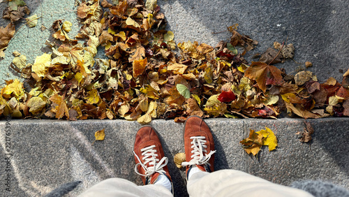 Looking Down at Shoes Beside a Pile of Fallen Leaves