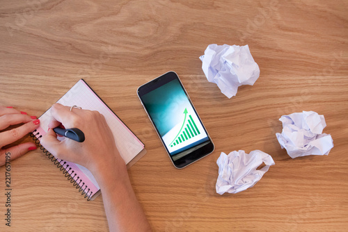 Hands holding smartphone with upward chart on screen, symbolizing mobile investing, fintech innovation, stock market growth and digital financial management.
