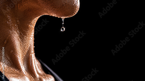 Extreme macro shot of a single sweat drop falling from a jawline on a black background