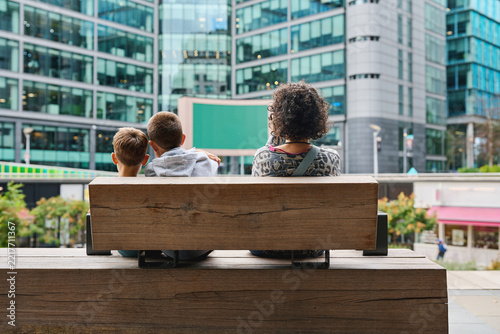 Canvas Print Mother and sons sitting on bench in modern London district