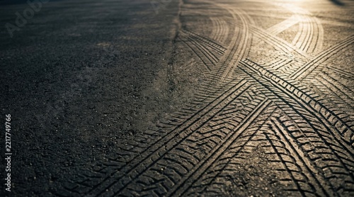 Tire tracks and skid marks crisscrossing on asphalt pavement surface