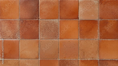 Terracotta square ceramic tile surface texture. Flat lay background of rustic earthy orange and brown floor tiles
